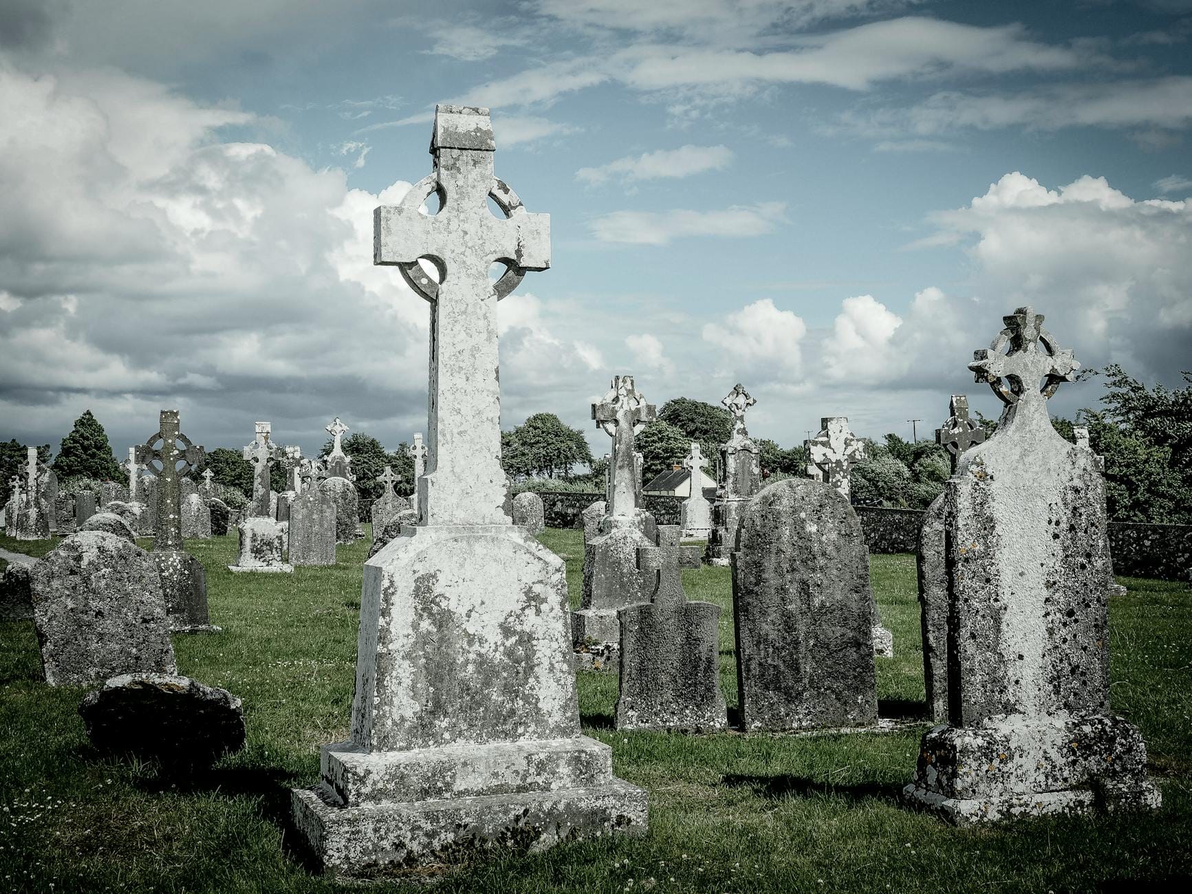 Stare nagrobki z celtyckimi krzyżami na cmentarzu pod pochmurnym niebem